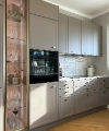 Cucina moderna con armadi grigi e vetrina, presentata da Nolte Kitchen.