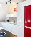 Cuisine moderne avec accents rouges, armoires blanches brillantes et îlot. Nolte Kitchen.