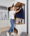 Une personne accroche une veste dans une entrée moderne conçue par Nolte Living.