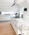 Eine moderne, helle Küche mit weißen Schränken und Insel; Nolte Küchen.