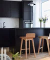 Eine moderne Küche mit schwarzen Schränken und Holzstühlen, gestaltet von Nolte Küchen.