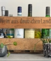 Une caisse en bois avec des bouteilles et des plantes crée une ambiance élégante, idéale pour les cuisines Nolte.
