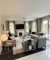 Ein Wohnzimmer mit Sofas und Sesseln, dekoriert mit Kissen und Decken, ist zu sehen. Nolte Living.