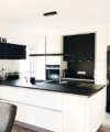 Cucina moderna in bianco e nero con isola e lampade a sospensione, design di Nolte Kitchen.