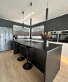 Cuisine moderne avec îlot sombre et tabourets, complétée par Nolte Kitchen.
