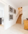 Un couloir lumineux avec escalier et vue sur une cuisine moderne de Nolte Kitchen.