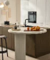 Dans la cuisine moderne, une table ronde avec des oranges et des bouteilles d'huile. Nolte Küchen.