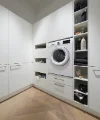 Ein moderner Hauswirtschaftsraum mit Waschmaschine und Regalen, gestaltet von Nolte Hauswirtschaftsräume.