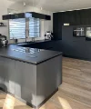Eine moderne Küche mit schwarzer Ausstattung und Kochinsel von Nolte Küchen.