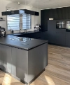 Cucina moderna con arredi neri e isola di cottura di Nolte Kitchen.