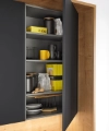 An open kitchen cabinet displays dishes and supplies. Nolte Kitchen.