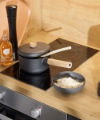 A modern kitchen with wood accents features a stove with a pot and rice bowl. Nolte Kitchen.