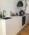 Cuisine moderne avec armoires blanches et sol en bois, Nolte Kitchen visible.