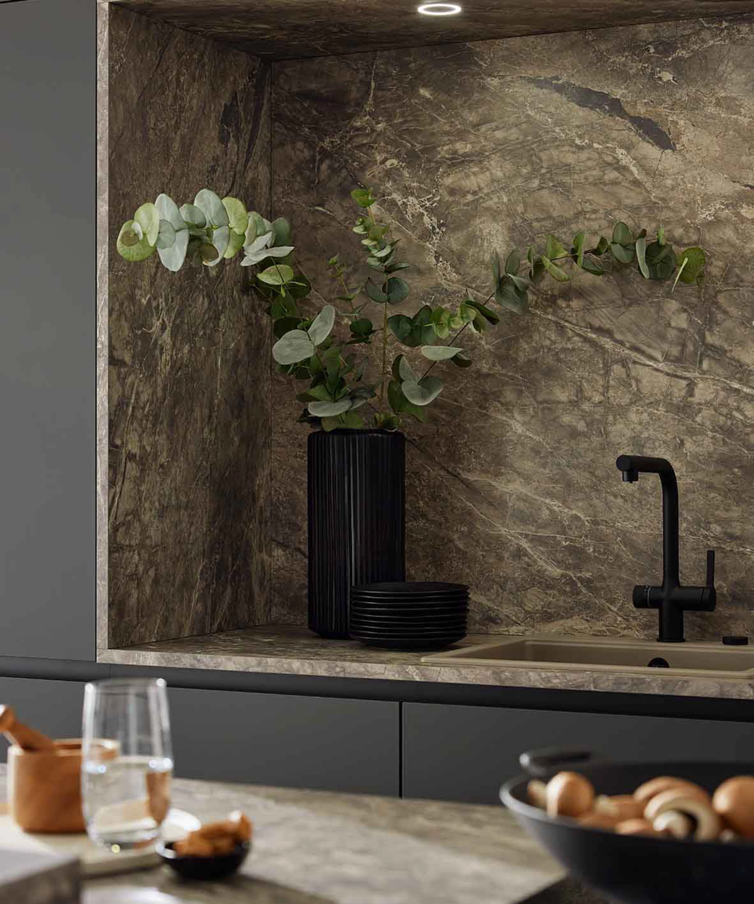 Eine elegante Küche mit dunklen Schränken und Marmoroptik, dekoriert mit einer Vase; Nolte Küchen.