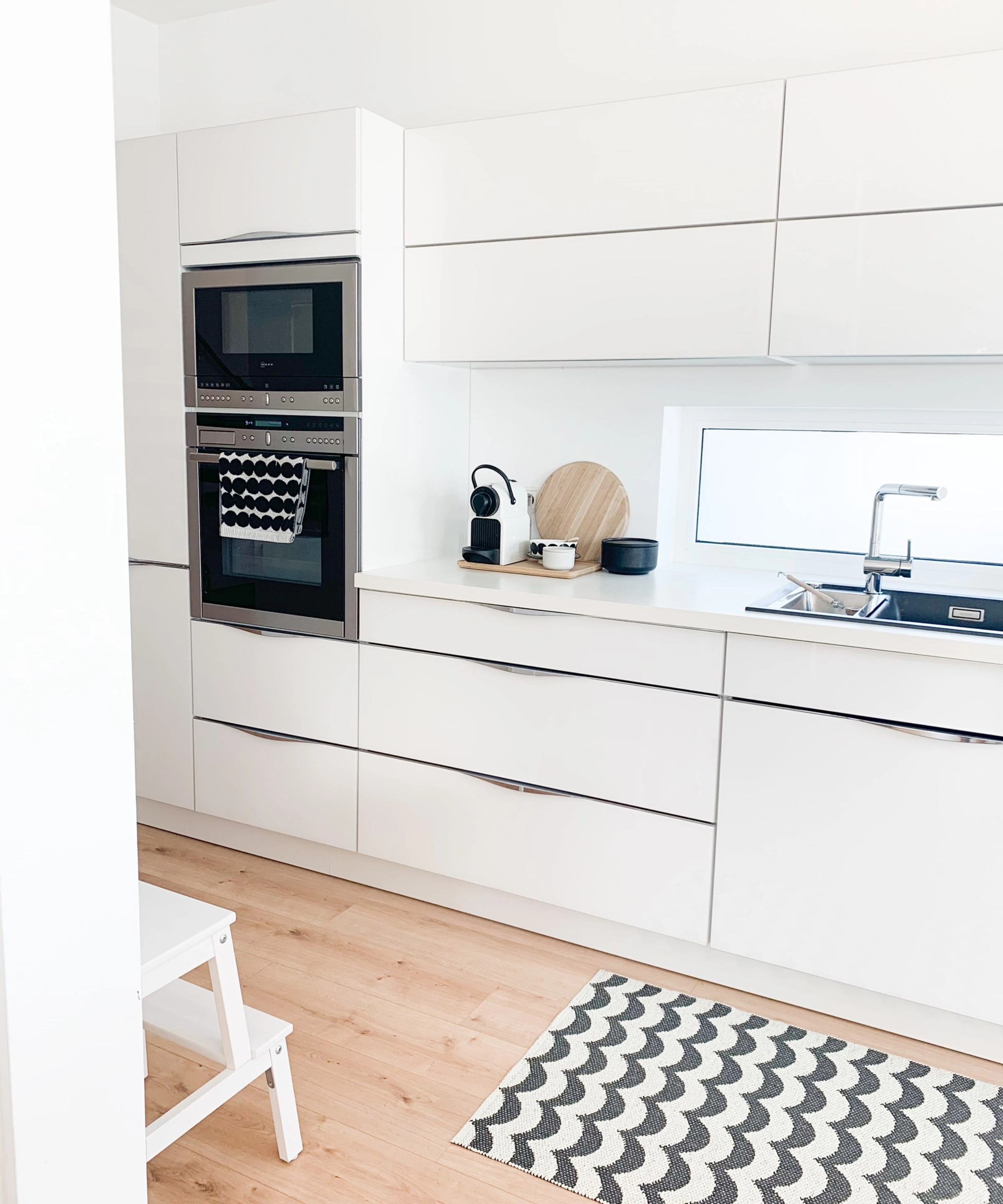 Cuisine moderne et lumineuse avec armoires blanches et tapis, élégamment conçue par Nolte Kitchen.