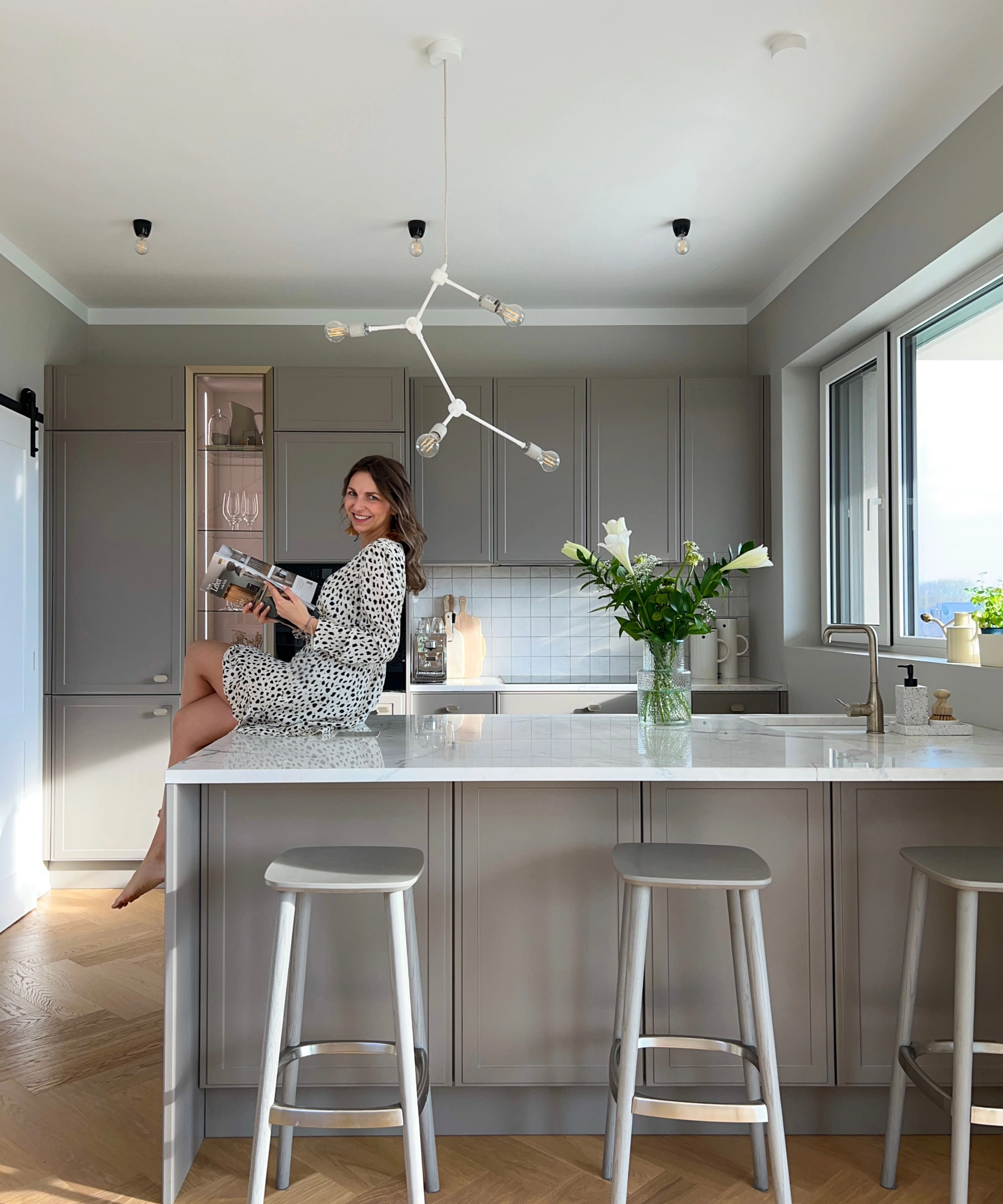 Une femme est assise sur un îlot de cuisine moderne avec des fleurs, Nolte Kitchen.