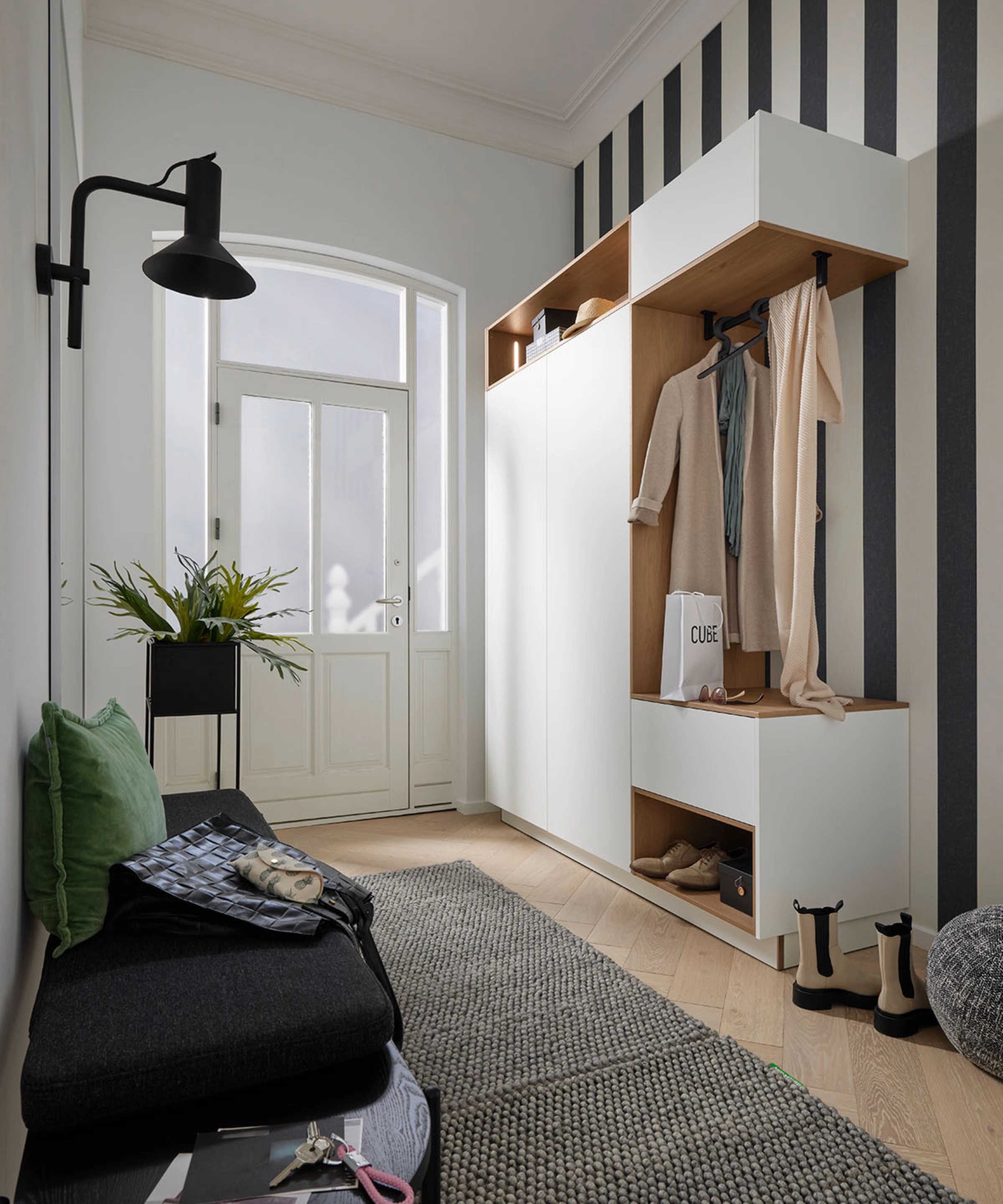 In de hal staan moderne meubels met opbergruimte en zitplek, geïntegreerd door Nolte Living.