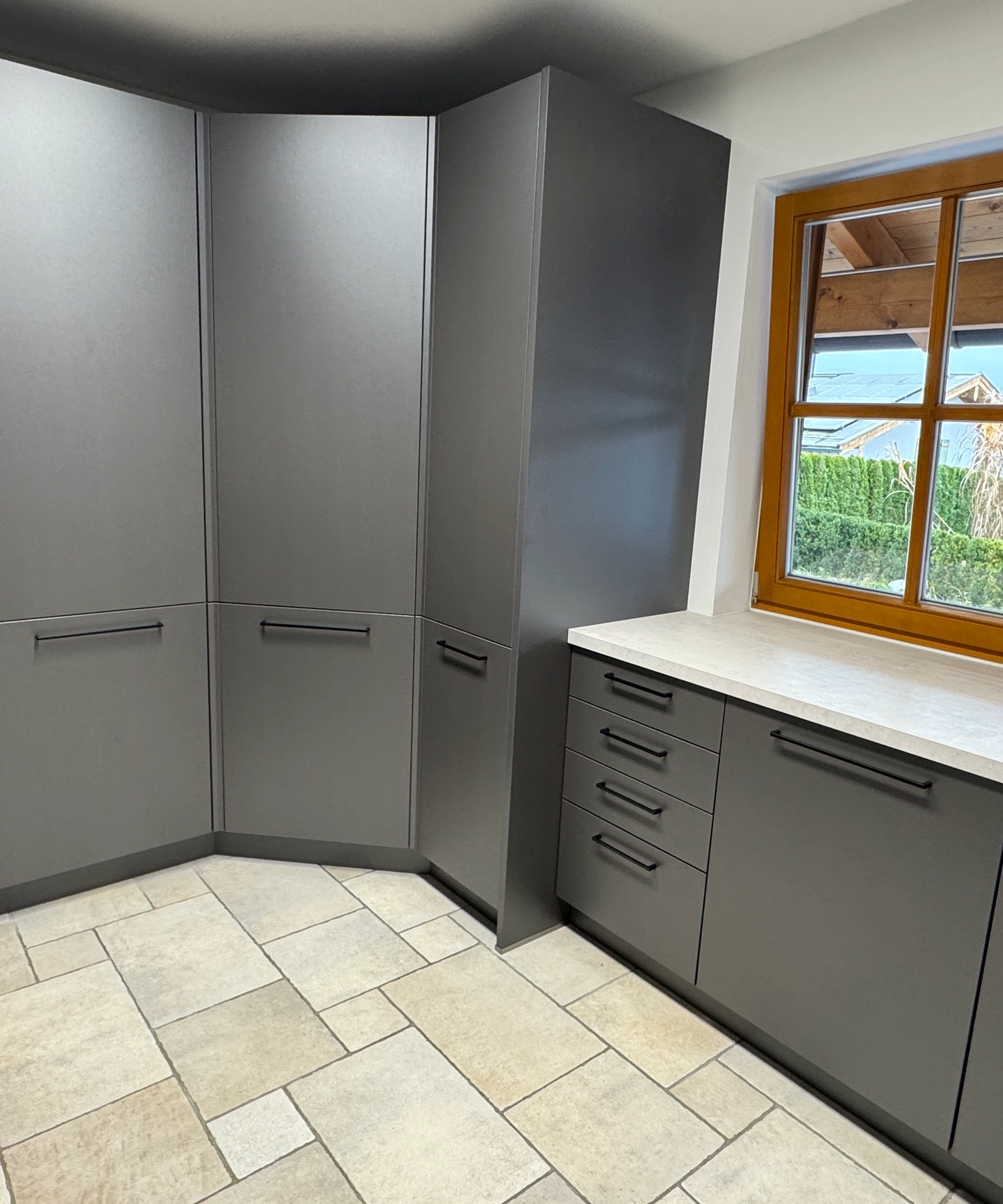 Cucina moderna grigia con armadi ad angolo e finestra, Nolte Kitchen.