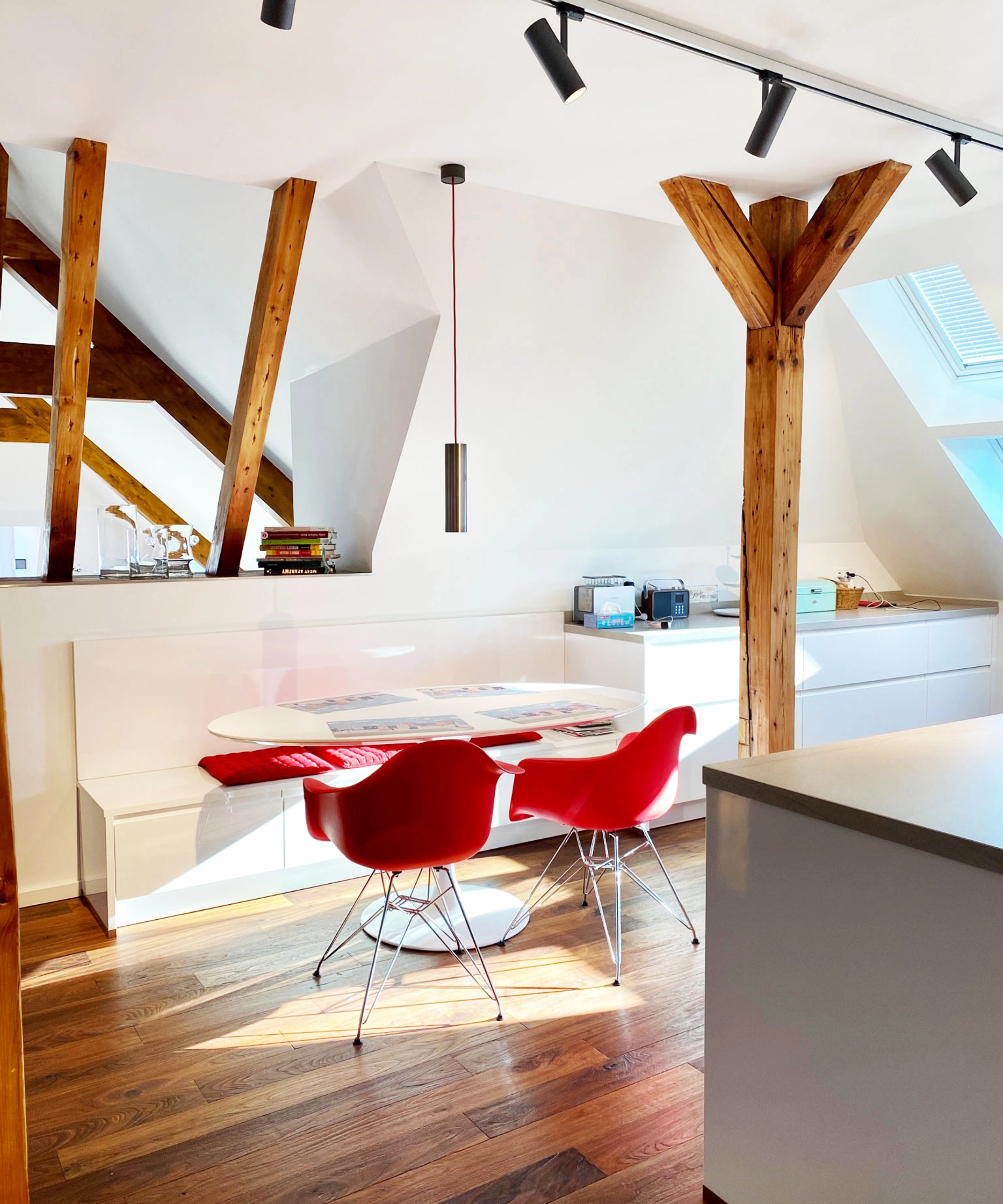 Une cuisine moderne avec poutres en bois et chaises rouges sous une fenêtre de toit. Nolte Kitchen.