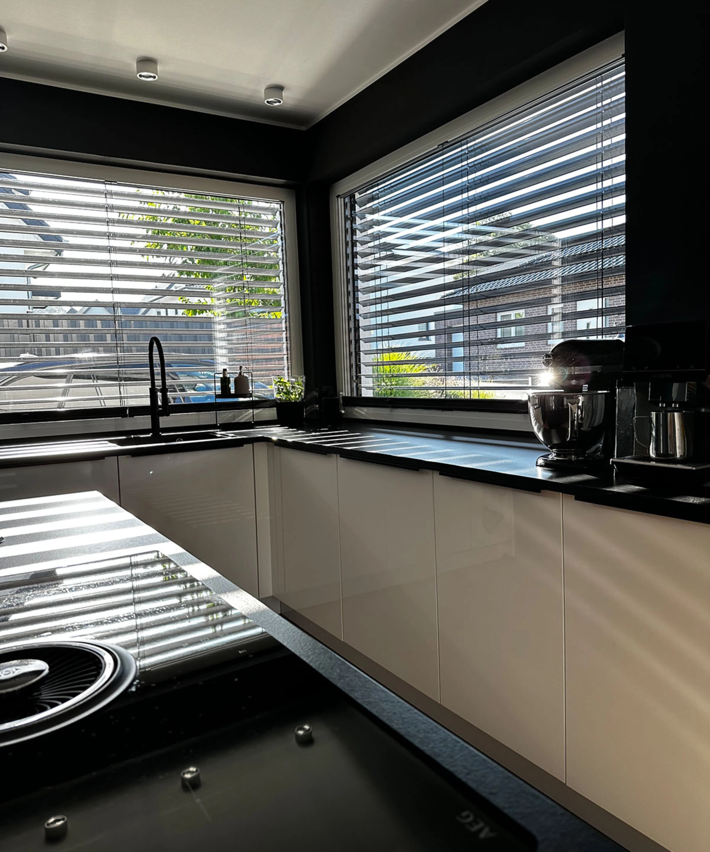 Une cuisine moderne avec des armoires blanches et de grandes fenêtres laissant entrer beaucoup de lumière. Nolte Kitchen.