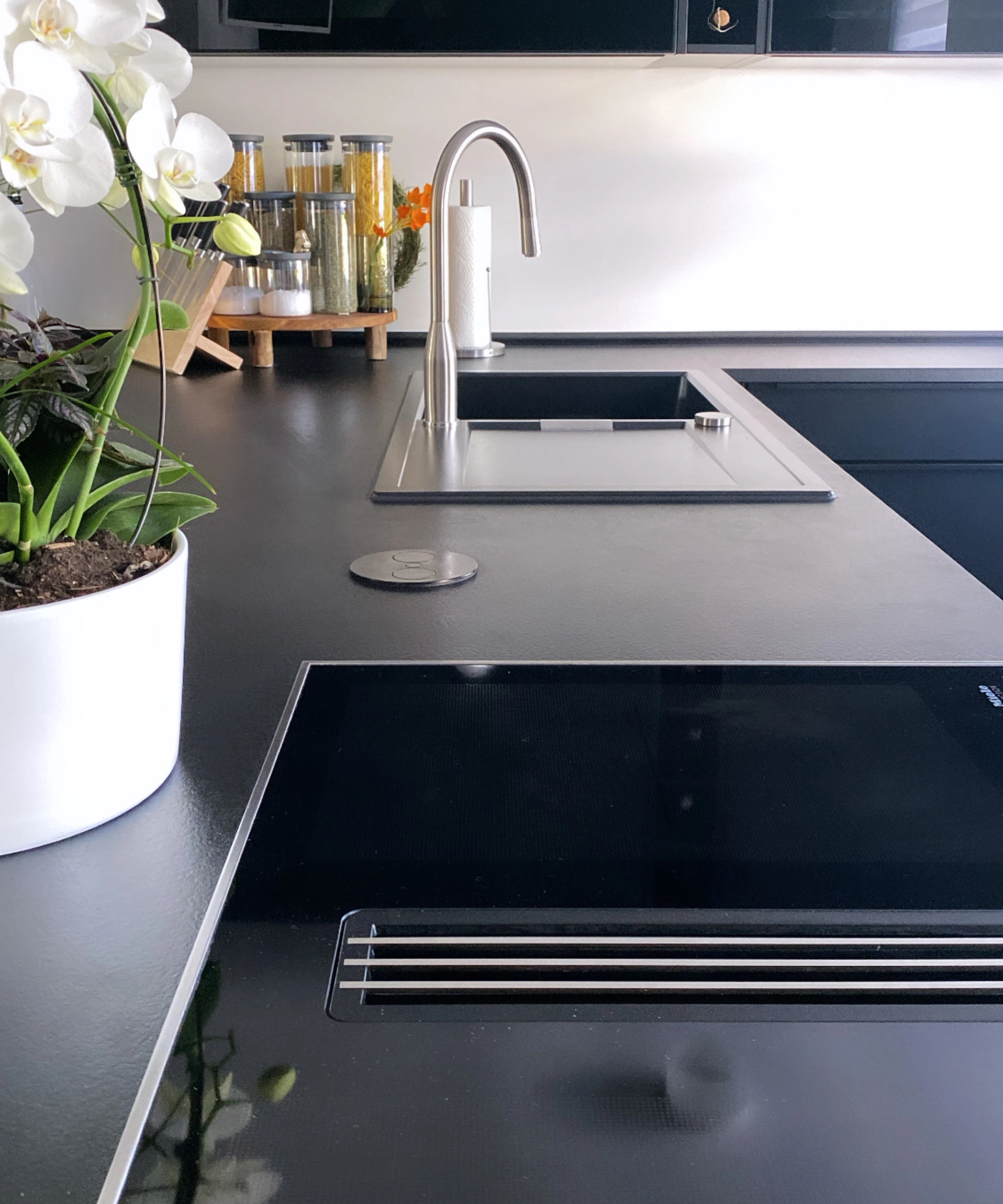Cuisine moderne avec plan de travail noir et orchidées blanches, Nolte Kitchen.