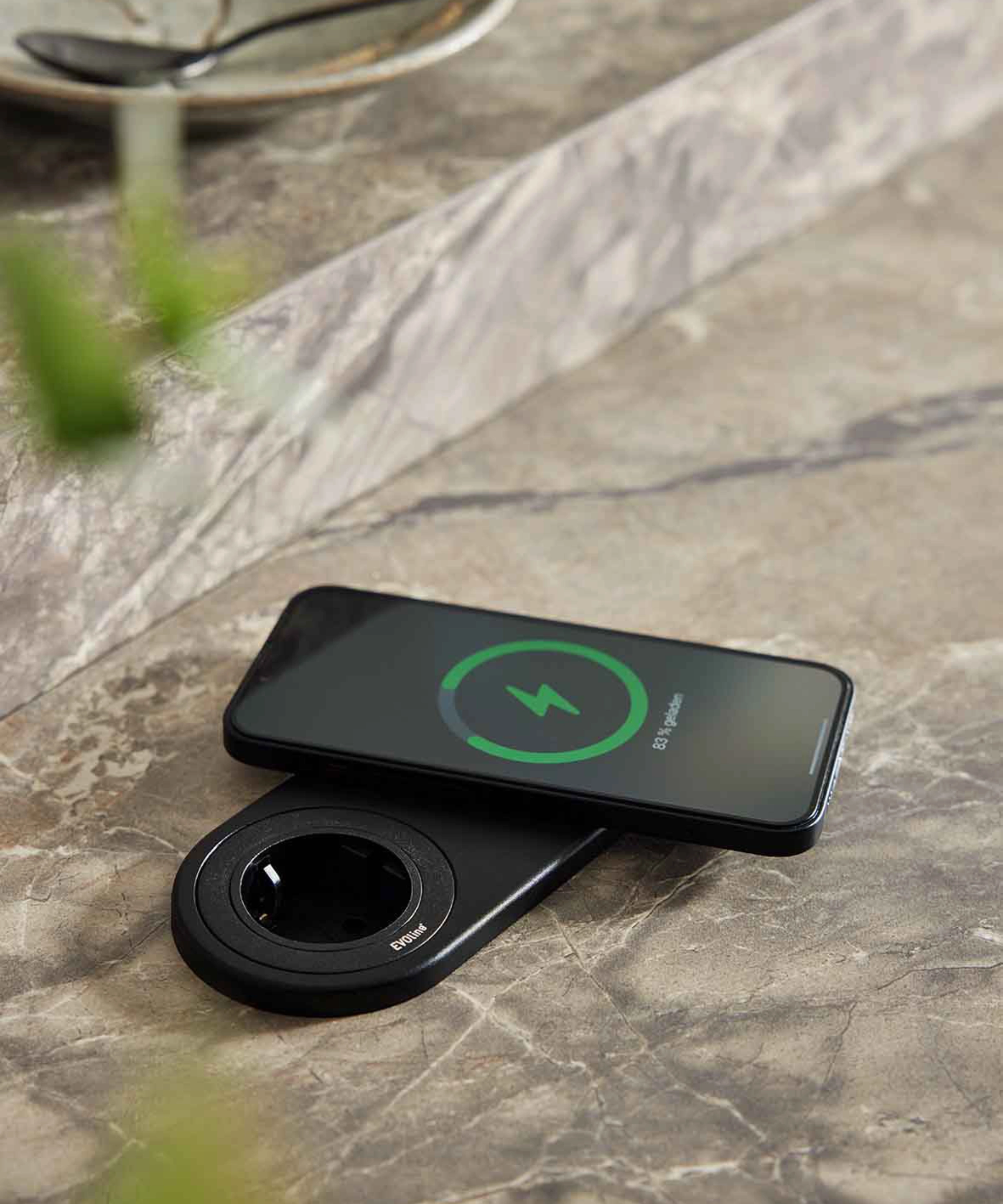 Ein Smartphone lädt kabellos auf einem Marmortisch.