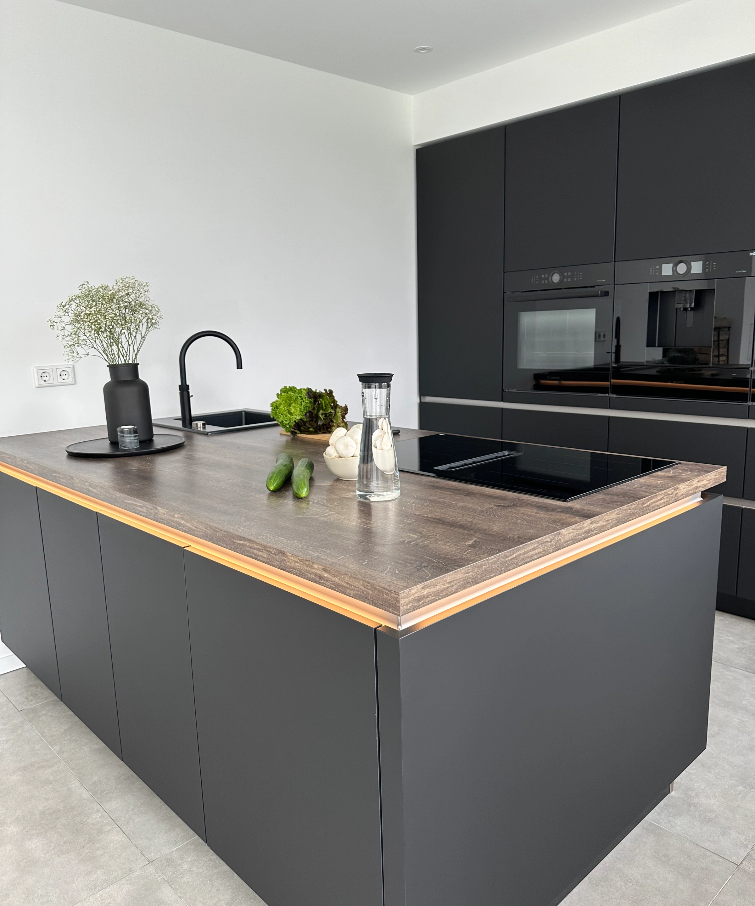 A modern kitchen with dark cabinets and wood accents, equipped by Nolte Kitchen.