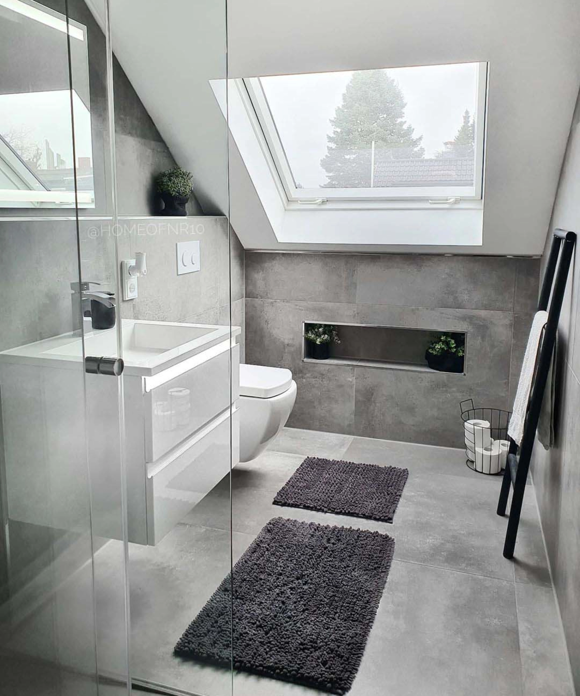 Salle de bain moderne avec carrelage gris, fenêtre de toit et déco minimaliste. Nolte SPA.