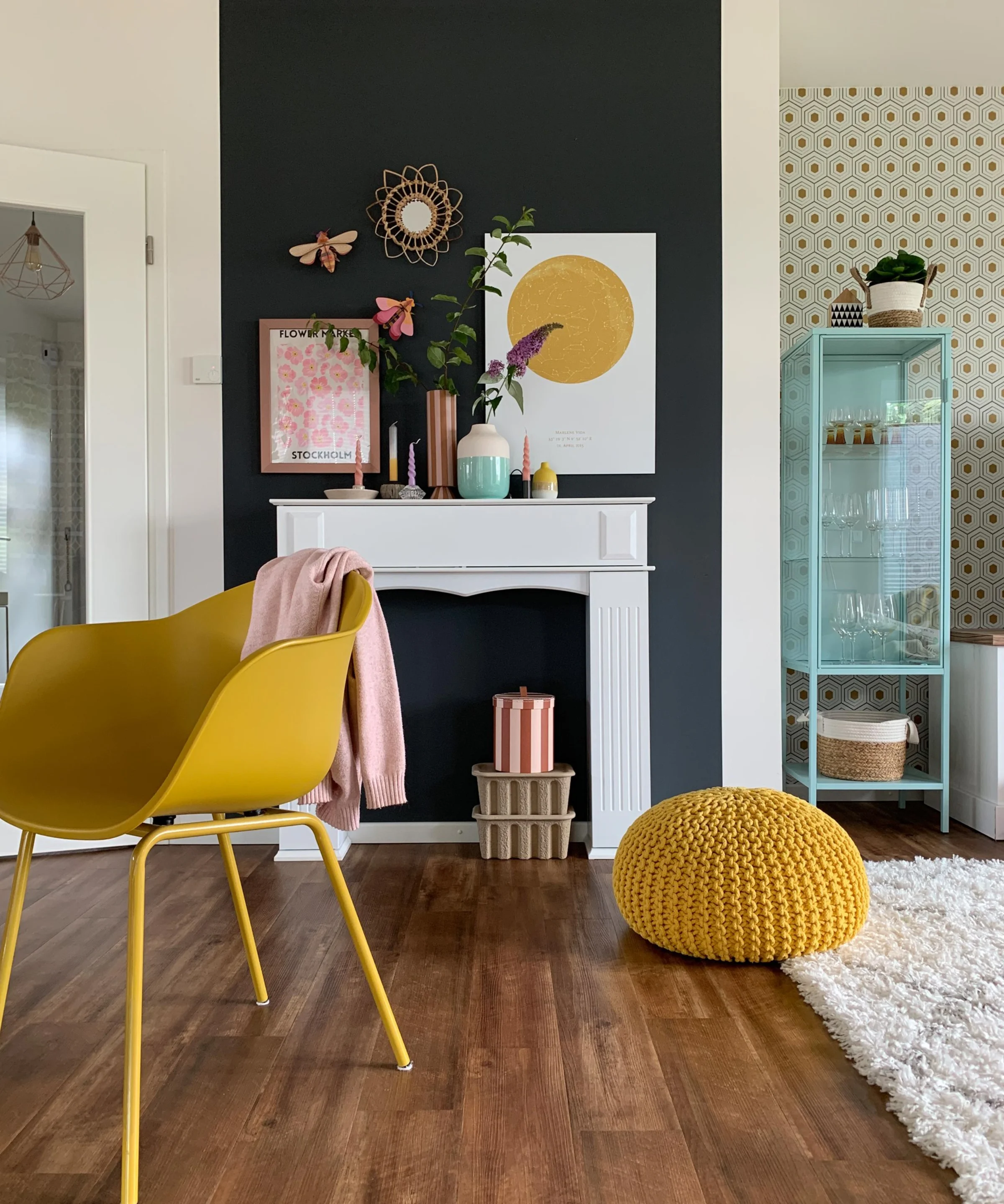 Ein stilvoll eingerichtetes Wohnzimmer mit gelbem Stuhl und Deko vor dunkler Wand; Nolte Living.