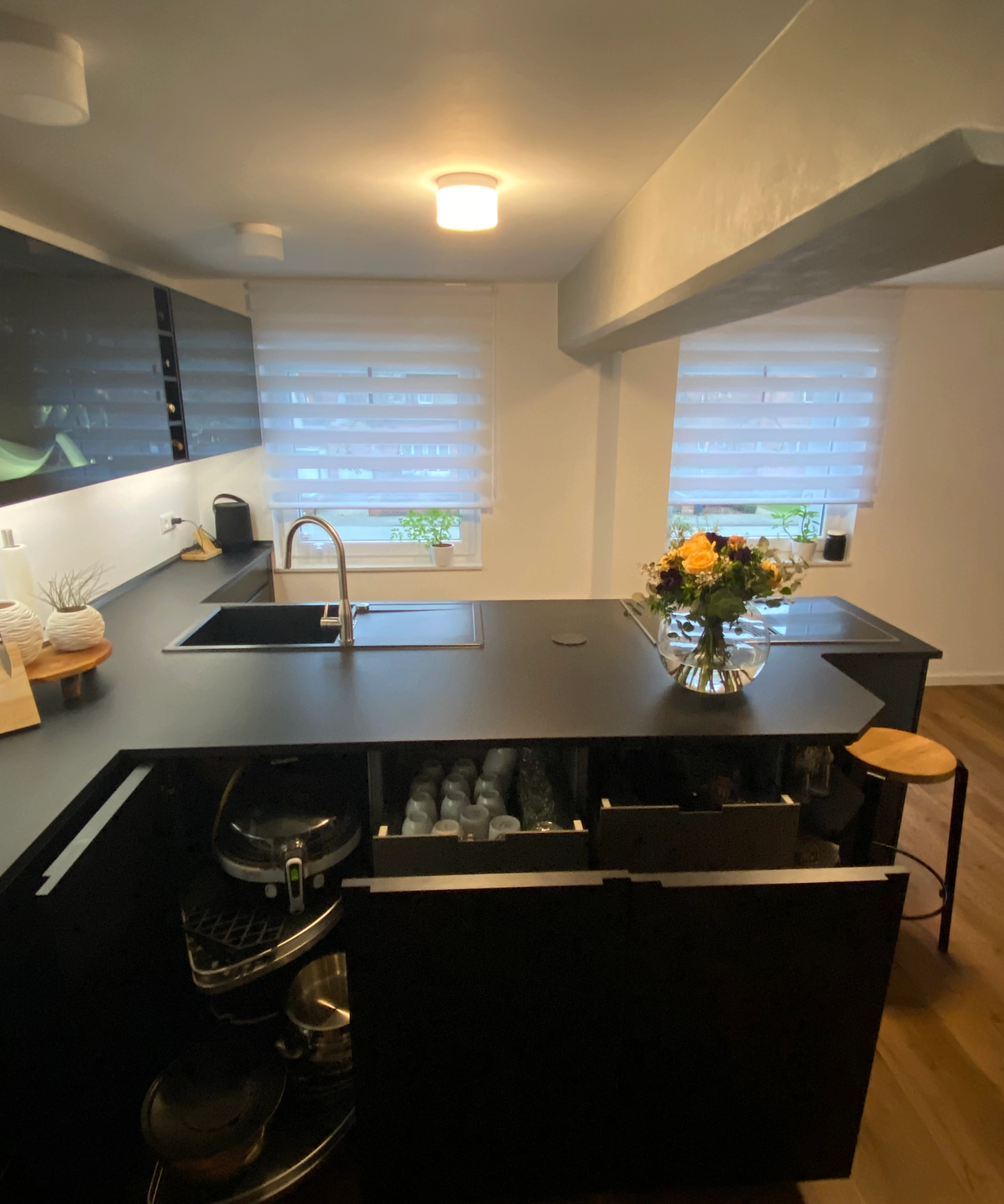Cuisine moderne avec armoires sombres et îlot, équipée par Nolte Kitchen.