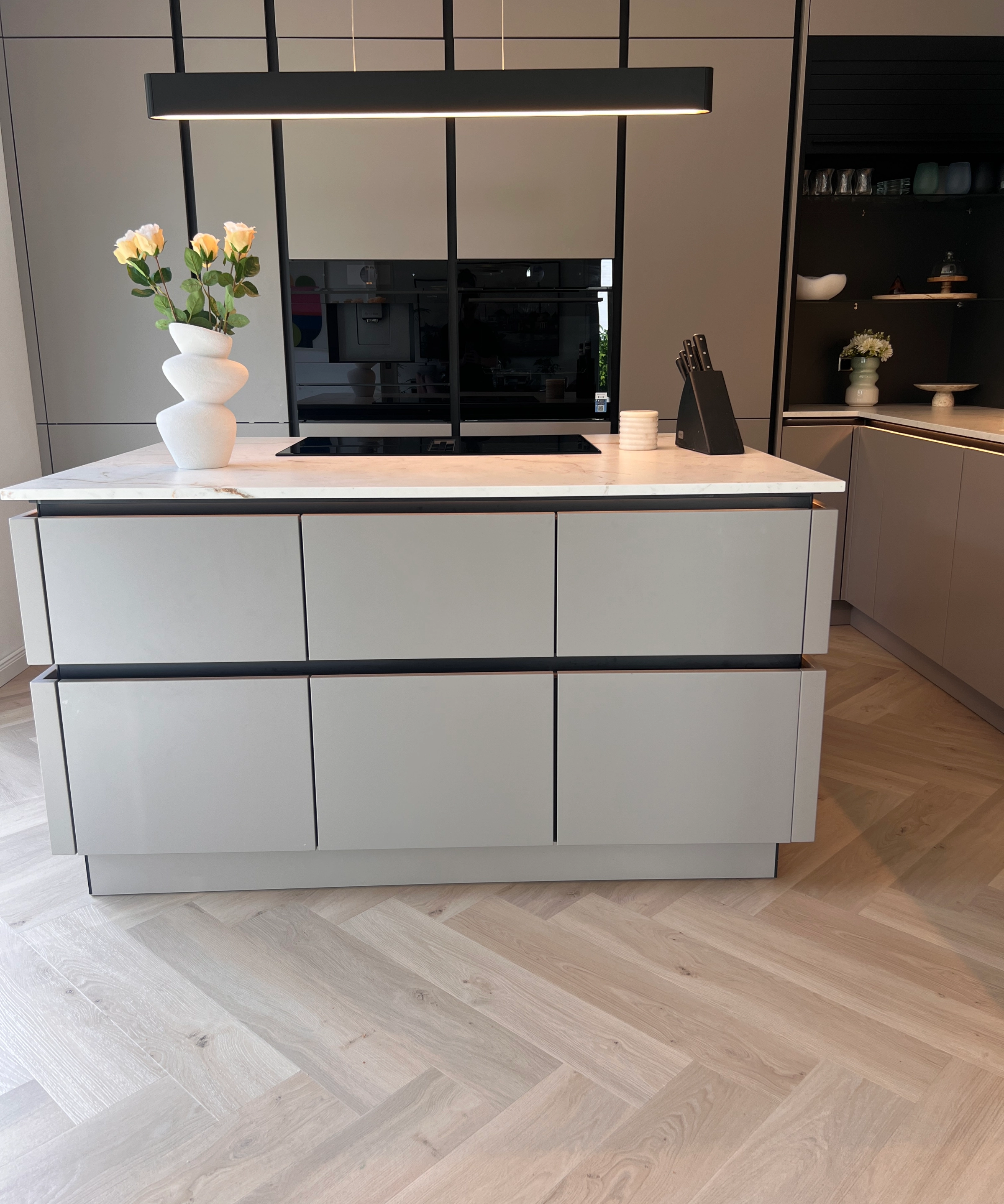 Cuisine moderne avec îlot et vases de fleurs, conçue par Nolte Kitchen.