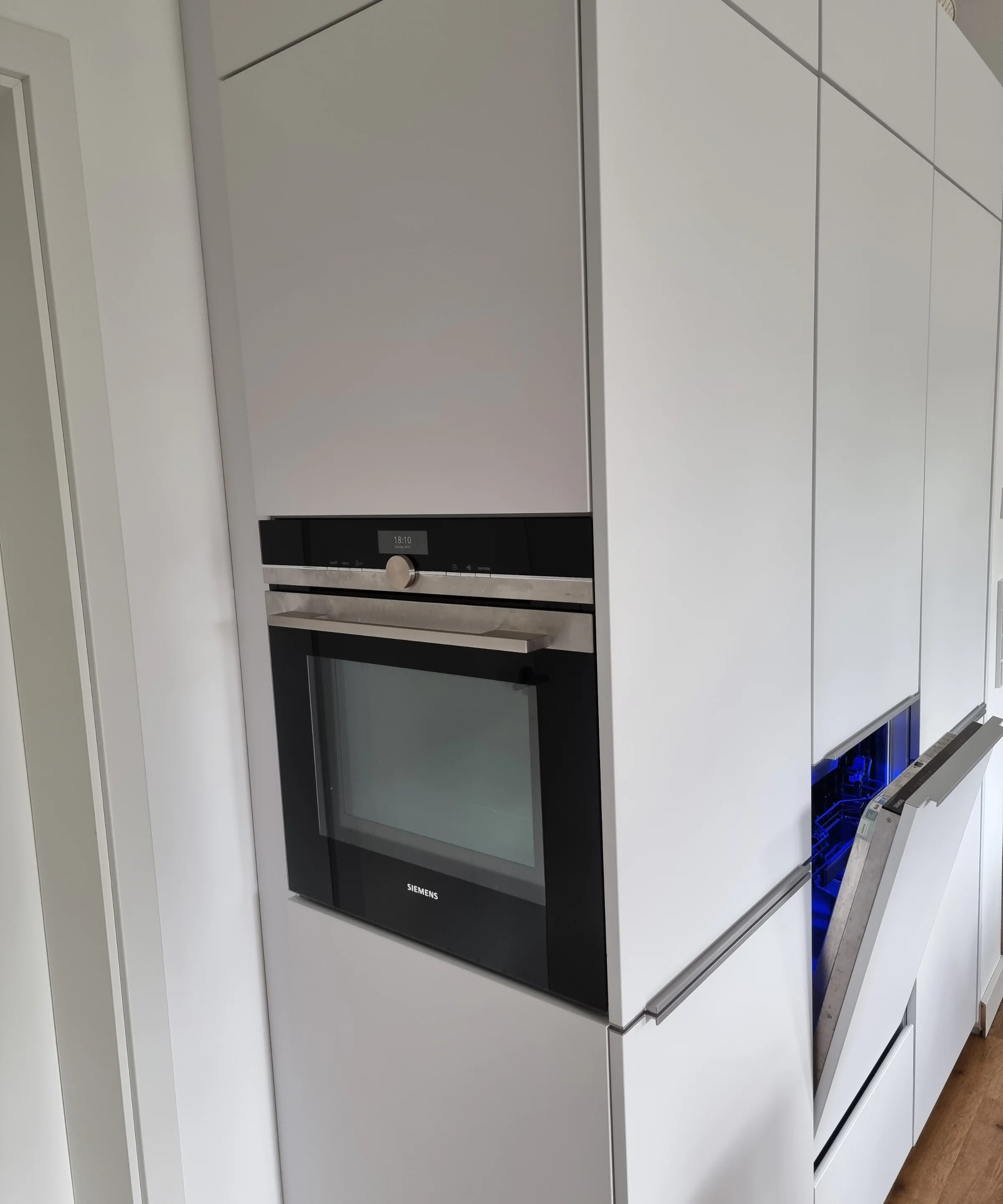Eine moderne Einbauküche mit weißen Schränken und integriertem Backofen, von Nolte Küchen.