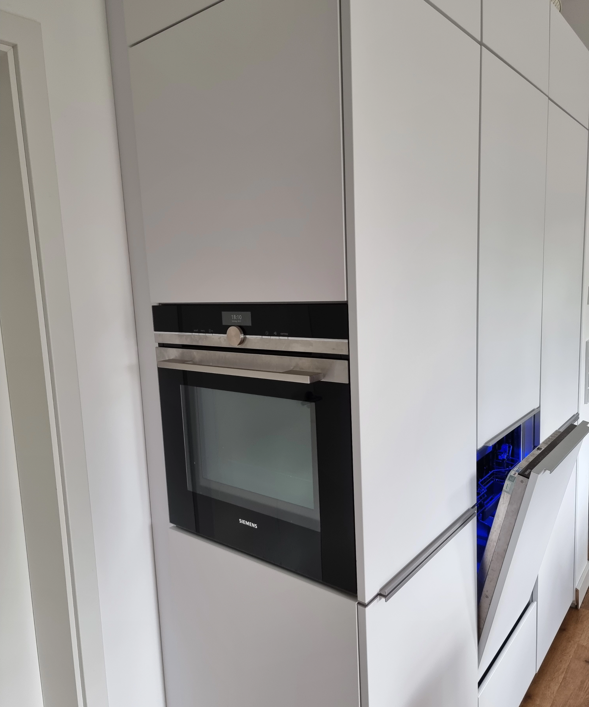 Eine moderne Einbauküche mit weißen Schränken und integriertem Backofen, von Nolte Küchen.