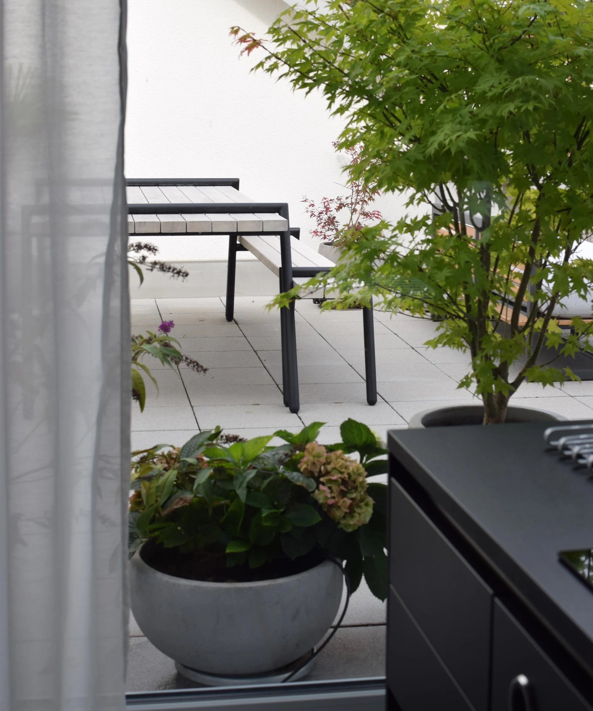 Ein moderner Außenbereich mit Pflanzen und Sitzmöbeln auf einer Terrasse.