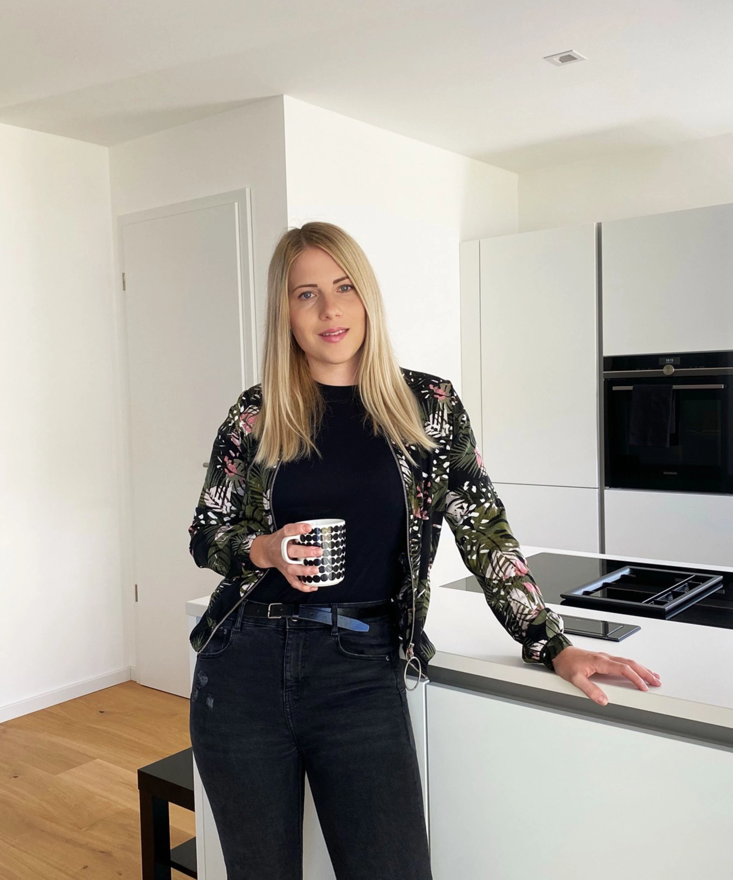 Une femme se tient dans une cuisine moderne avec des armoires blanches, Nolte Kitchen.