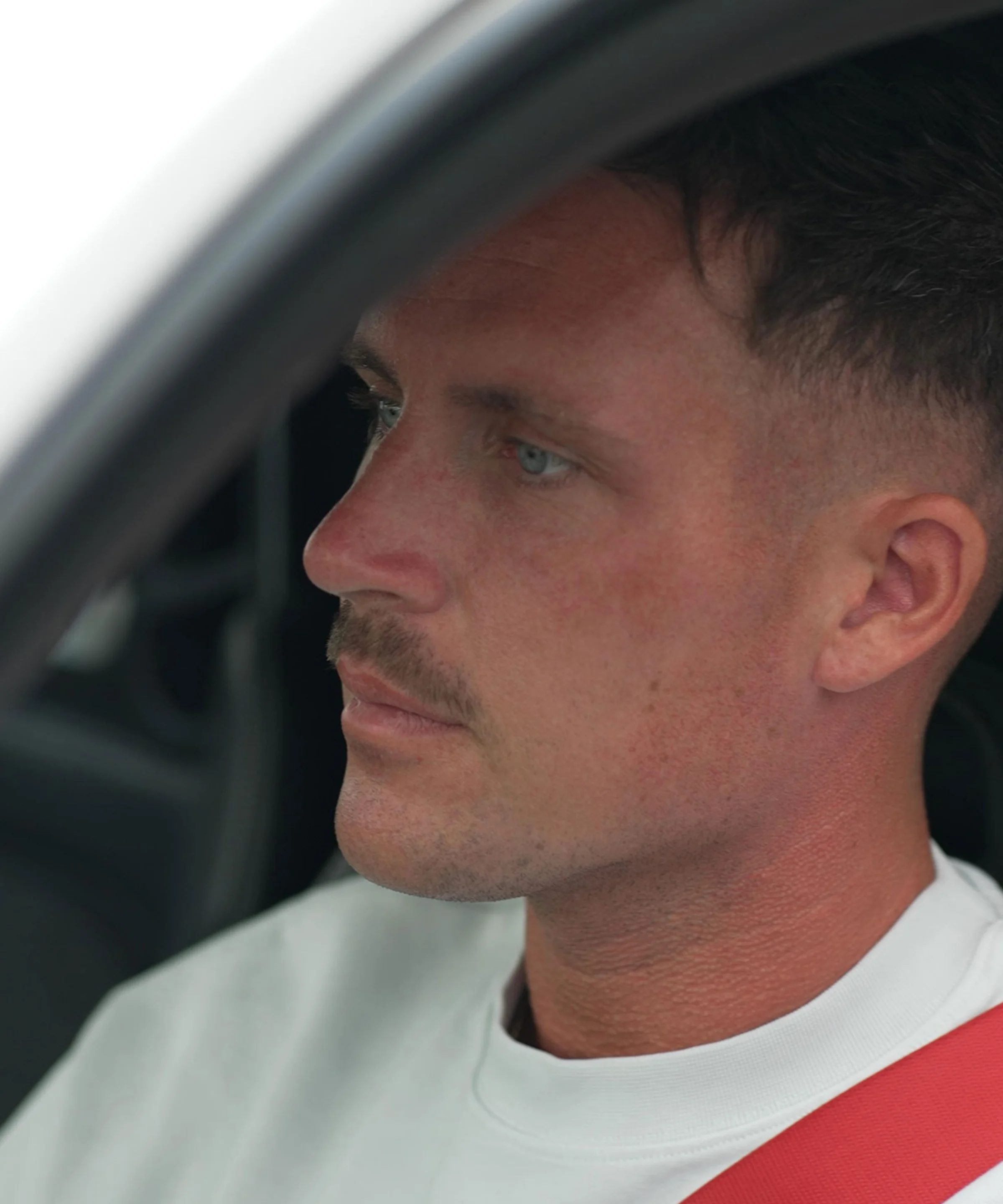 Un homme est assis dans une voiture avec une ceinture de sécurité rouge.