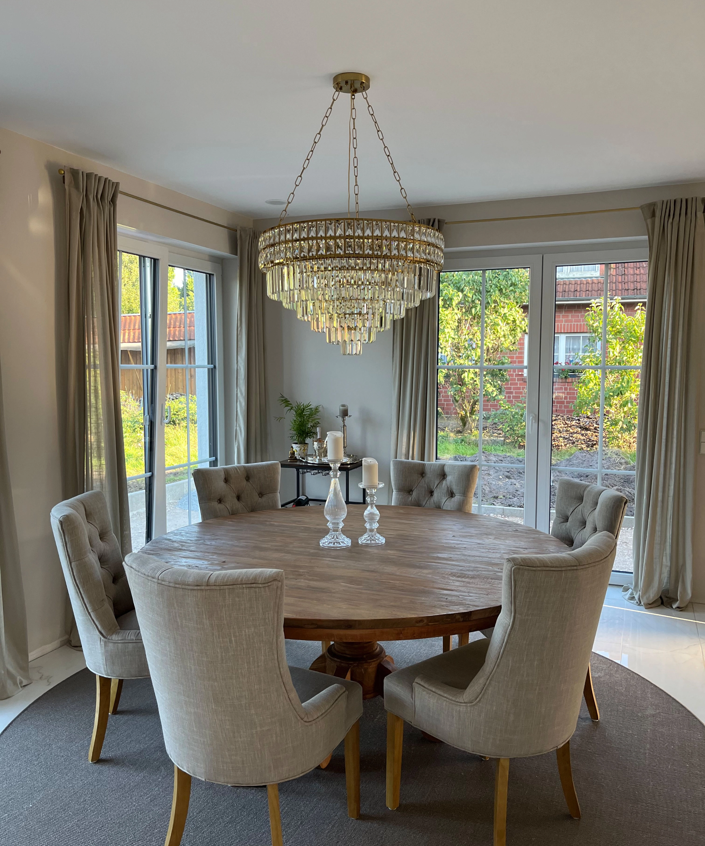 Salle à manger élégante avec table ronde en bois et chaises rembourrées sous un lustre. Nolte Living.