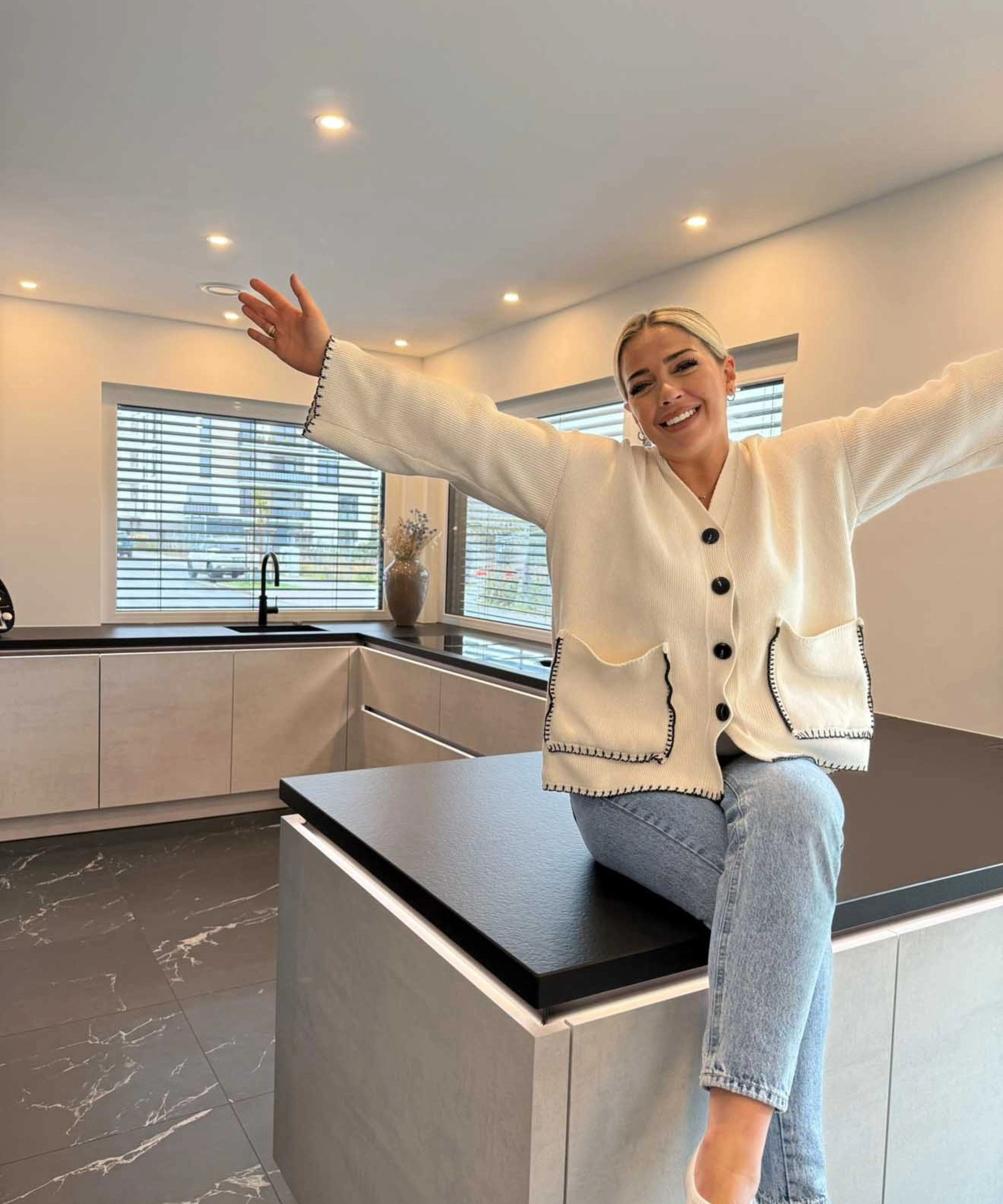 Une femme est assise dans une cuisine moderne au design Nolte.