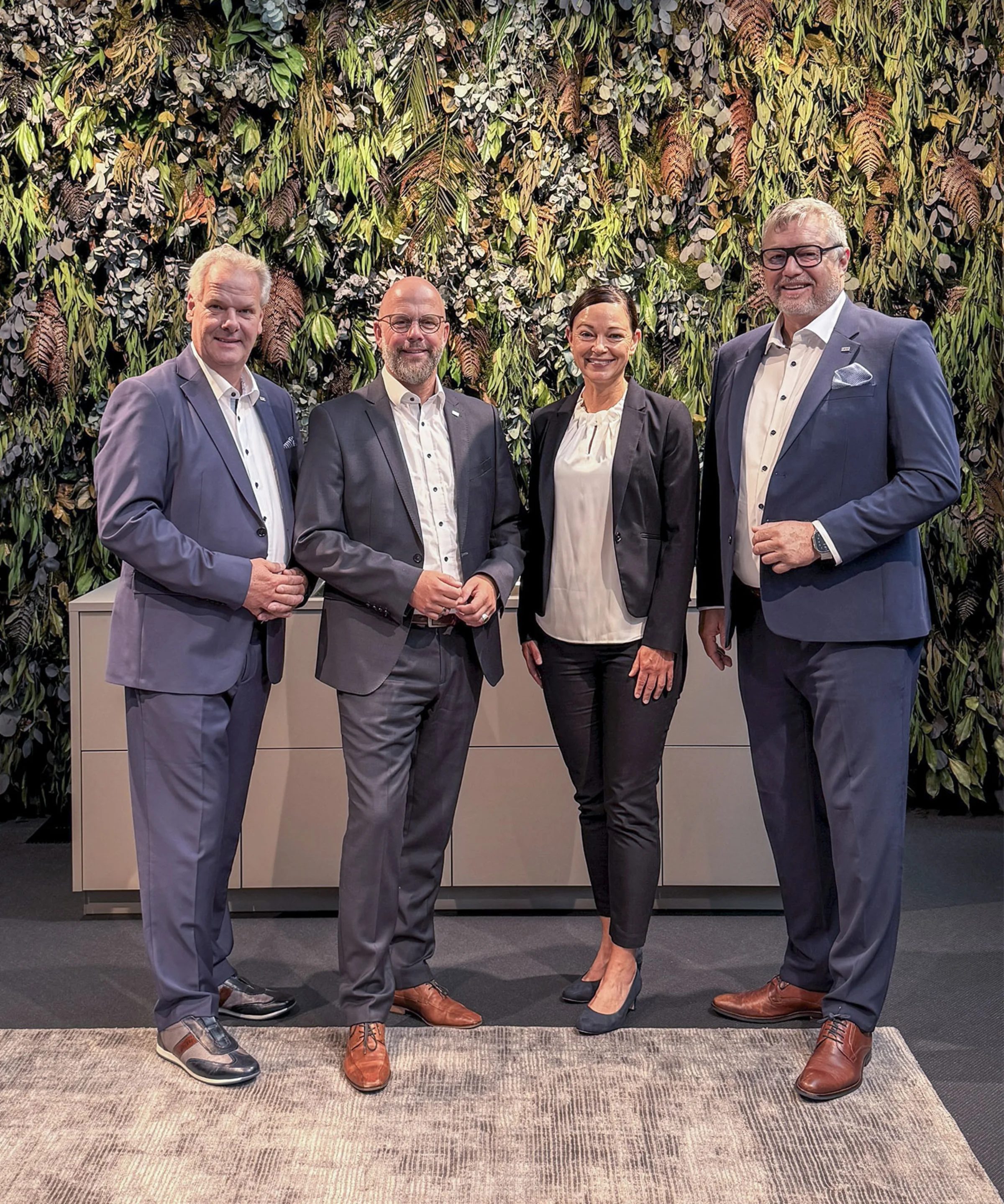 A group of four people stands in front of a large sign reading "Nolte Kitchen".