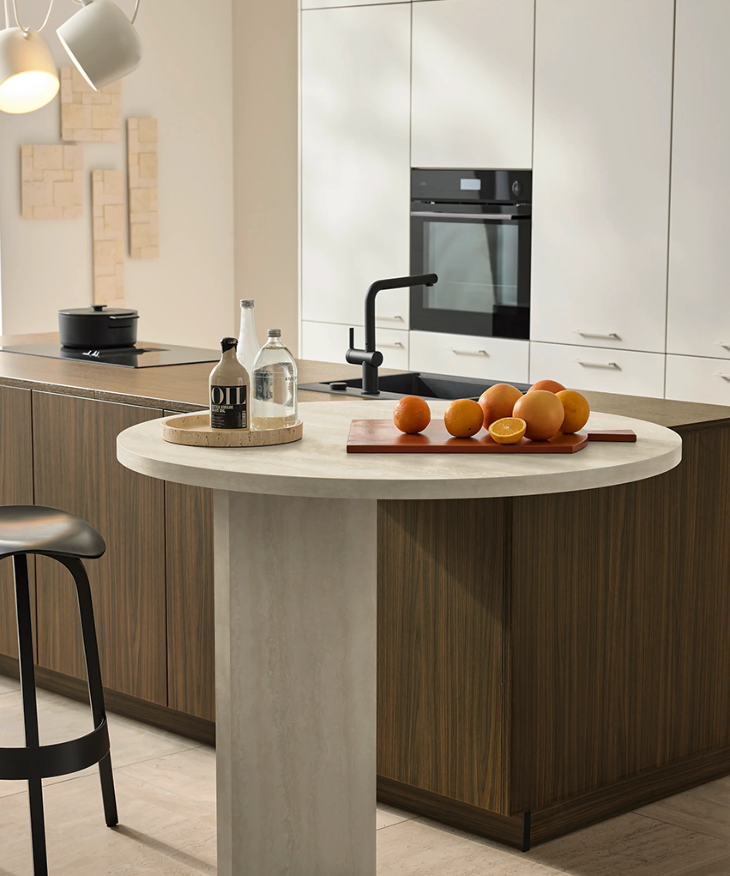 Dans la cuisine moderne, une table ronde avec des oranges et des bouteilles d'huile. Nolte Küchen.
