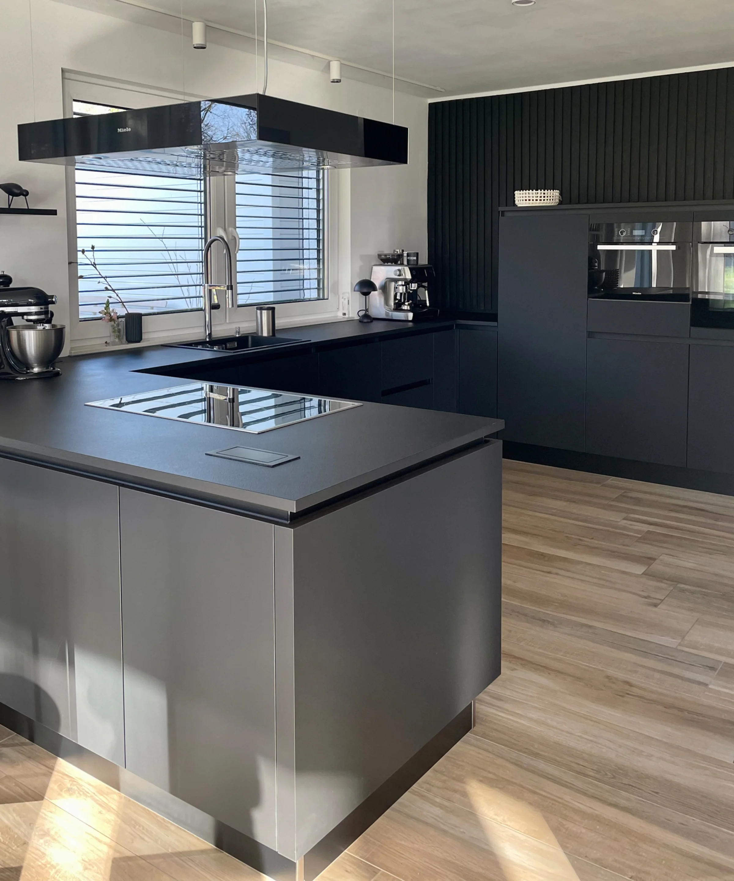 Eine moderne Küche mit schwarzer Ausstattung und Kochinsel von Nolte Küchen.
