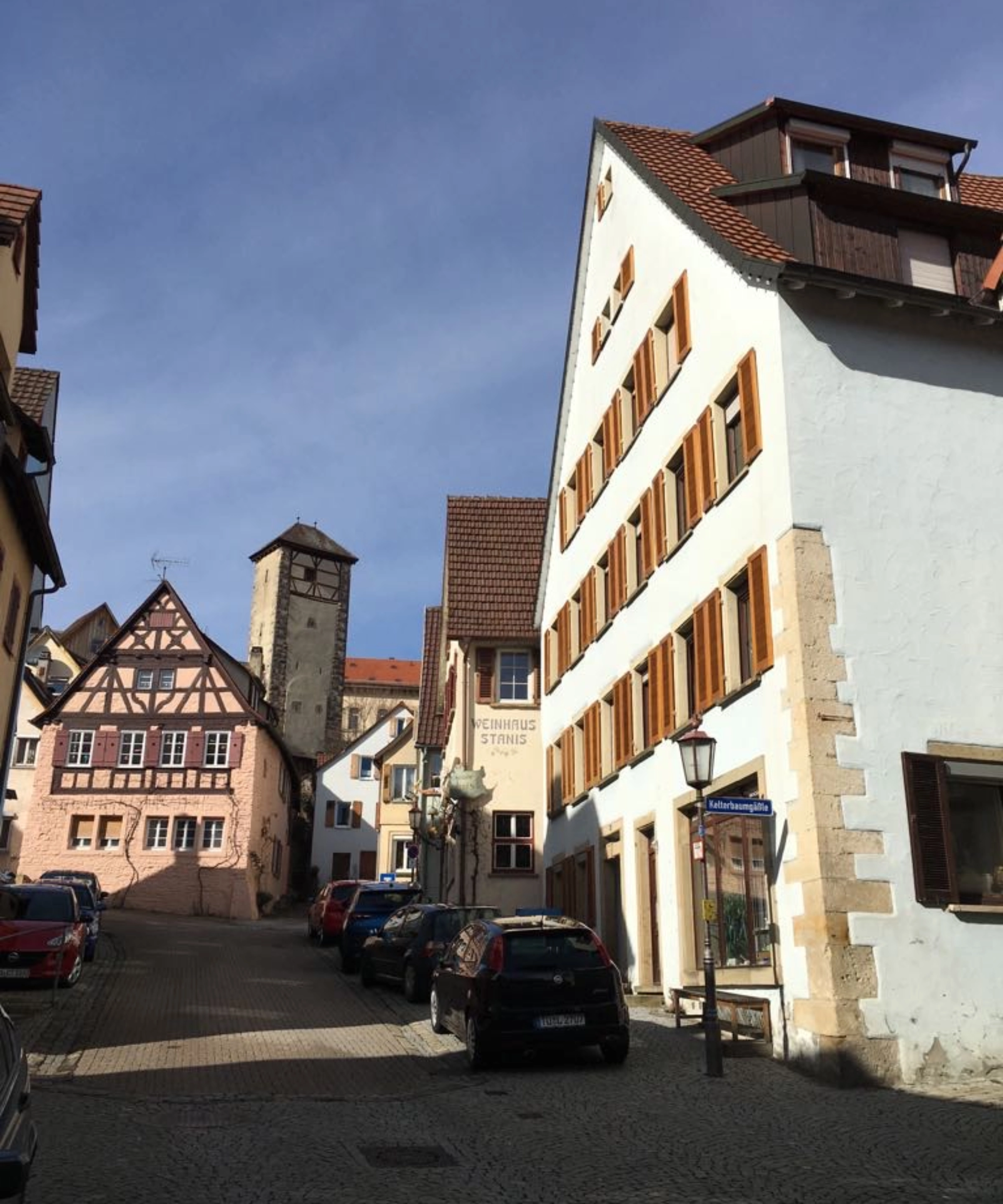 Une rue pittoresque de vieille ville avec des maisons à colombages et un clocher en arrière-plan.