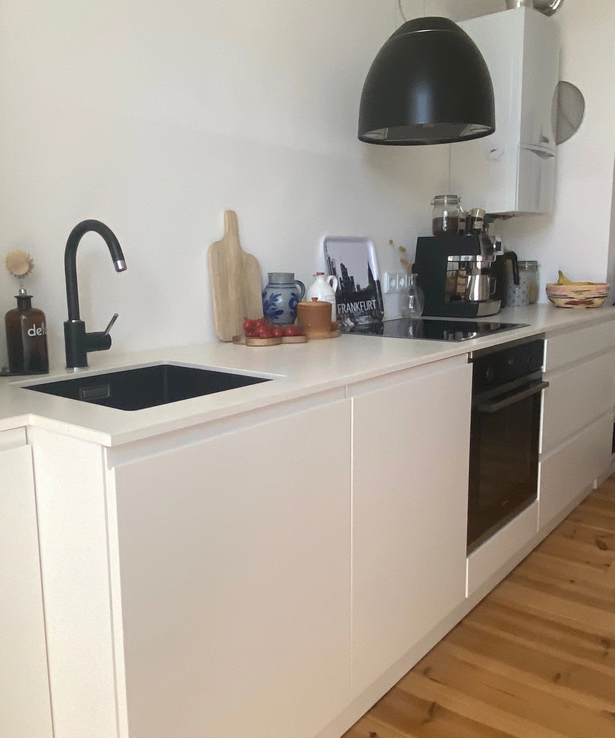 Cuisine moderne avec armoires blanches et sol en bois, Nolte Kitchen visible.