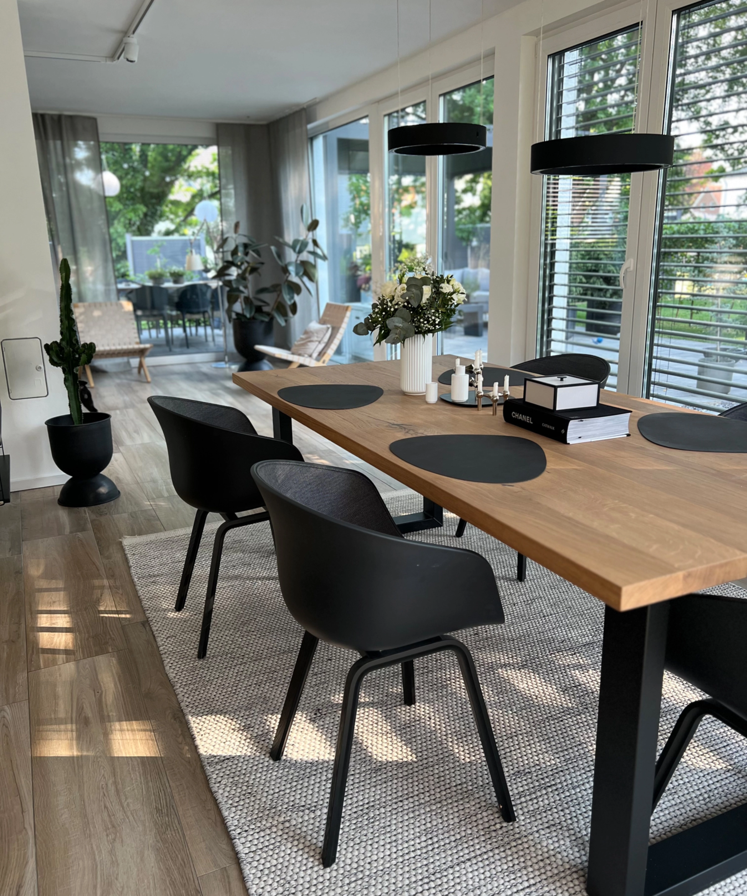 Ein moderner Essbereich mit Holztisch und schwarzen Stühlen, umgeben von großen Fenstern, im Stil von Nolte Living.