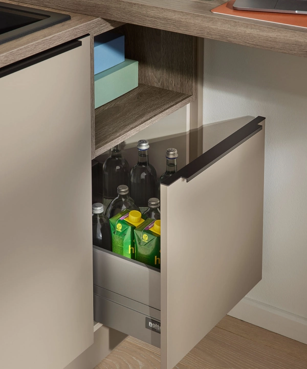 An open kitchen cabinet displaying bottles and crates, part of Nolte Kitchens.