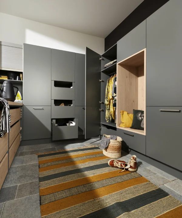Une buanderie avec des armoires et étagères grises, conçue par Nolte Utility Rooms.