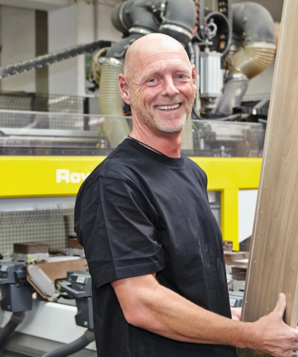 Eine Person arbeitet in einer modernen Werkstatt mit Holz und Maschinen.