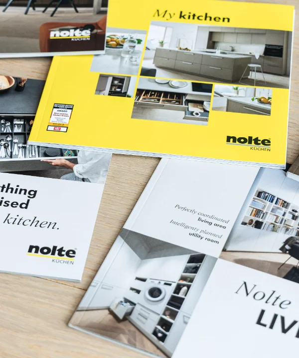 Vier Broschüren über Nolte Küchen, Nolte Living und NolteNeo-Designs liegen auf einem Tisch.