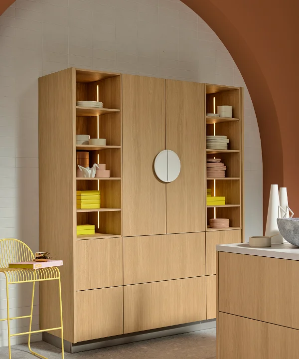 Moderner Hochschrank in Eiche Bianco mit offenen Regalfächern und integrierter Beleuchtung unter rundem Bogen in Terrakottaton. Warmes Farbkonzept mit gelben Akzenten und minimalistischem Design von nolteneo.