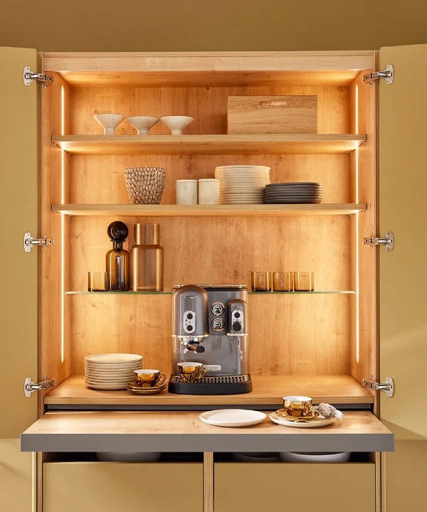 An open kitchen cabinet with dishes and a coffee machine. Nolte Kitchens.